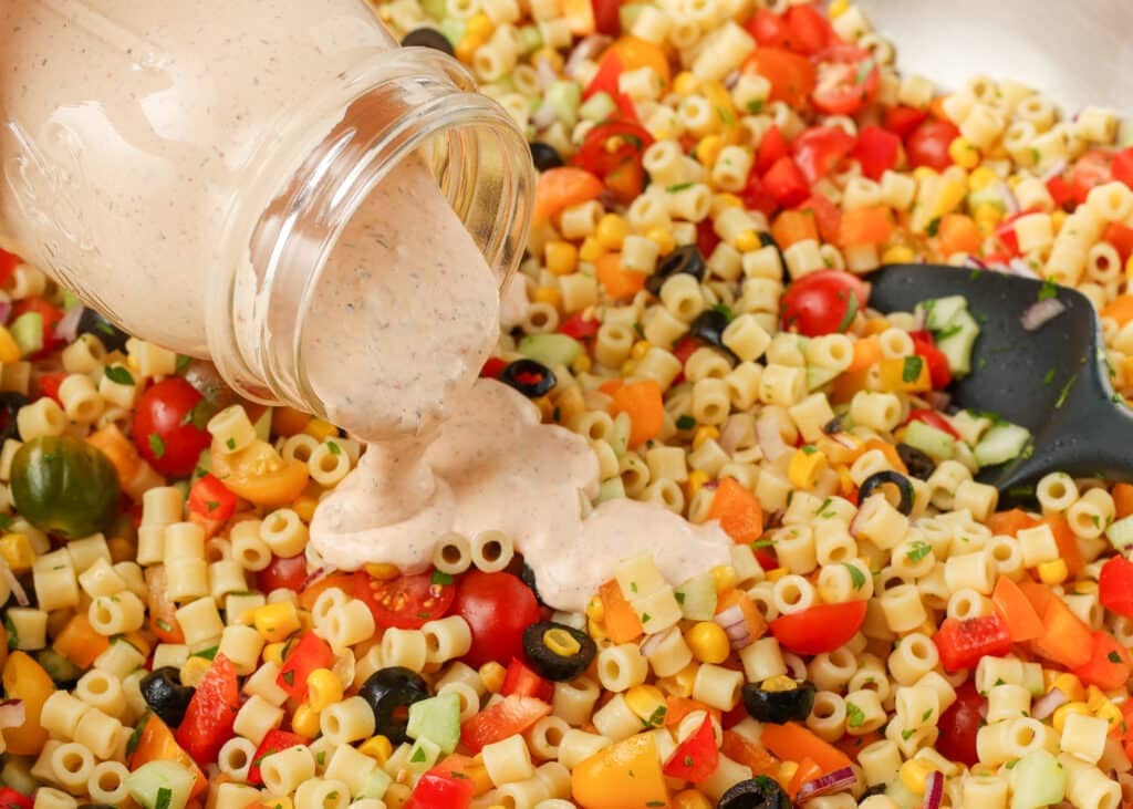 A horizontally aligned shot, showing the creamy chipotle ranch dressing being poured over the mixed ingredients.