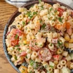 A top down image of this delightfully spicy pasta salad in a bowl over a wooden tabletop.