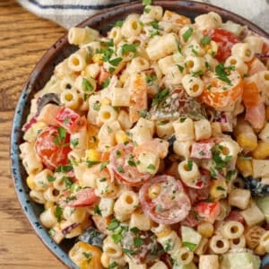 A top down image of this delightfully spicy pasta salad in a bowl over a wooden tabletop.