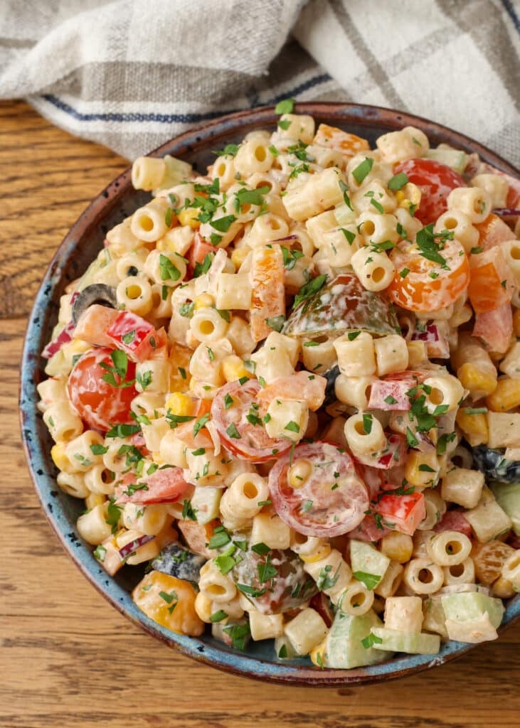 A top down image of this delightfully spicy pasta salad in a bowl over a wooden tabletop.