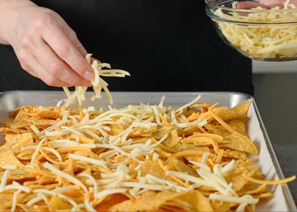 sprinkling cheese over tortilla chips
