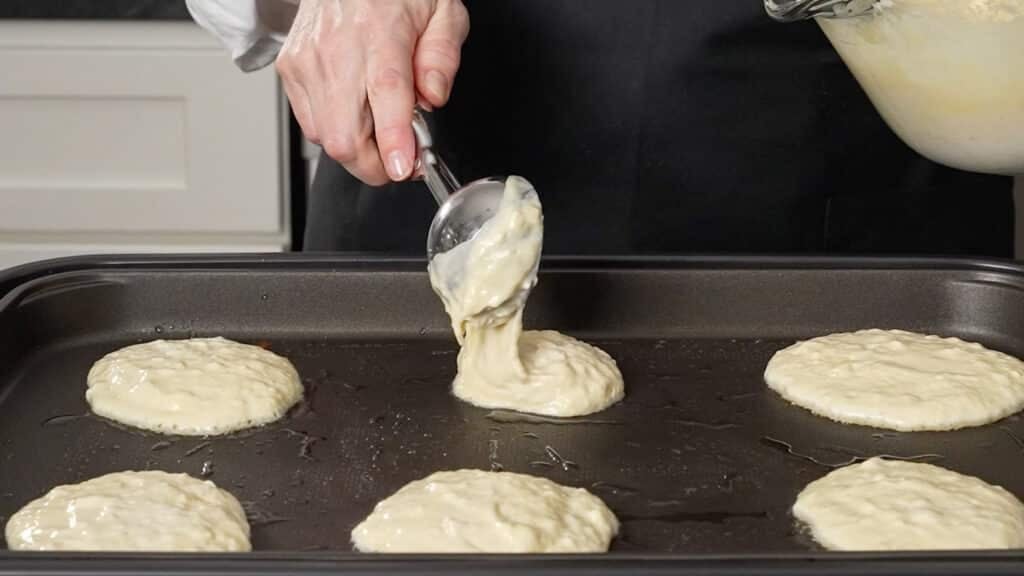 pouring batter onto griddle with a metal scoop