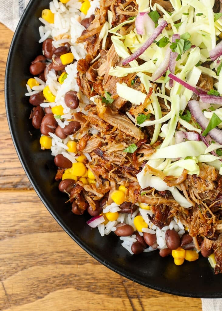 A vertically aligned, top down, close up image of the pork, cabbage and red onion in this bowl.