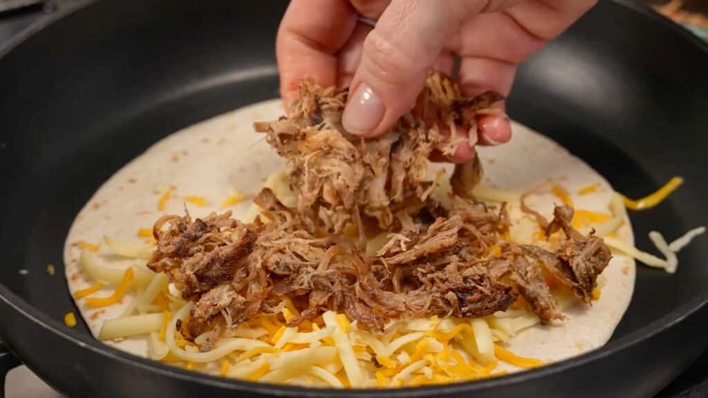adding carnita meat to open quesadilla