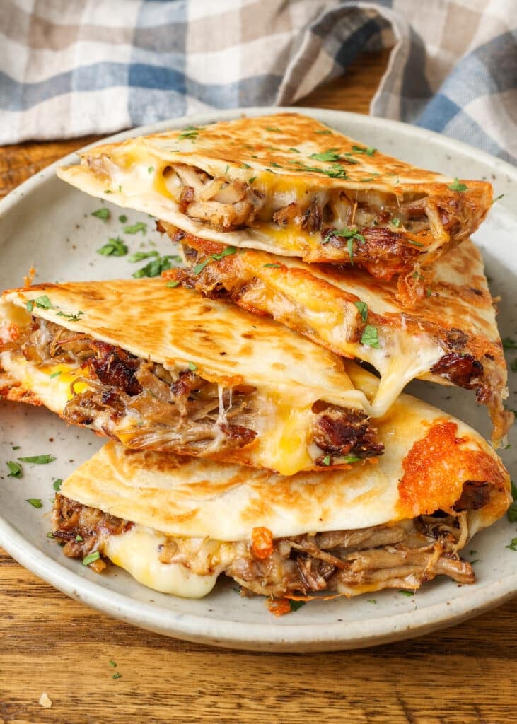 Carnitas meat has been added to the cheese and cooked in a flour tortilla to create these quesadillas.
