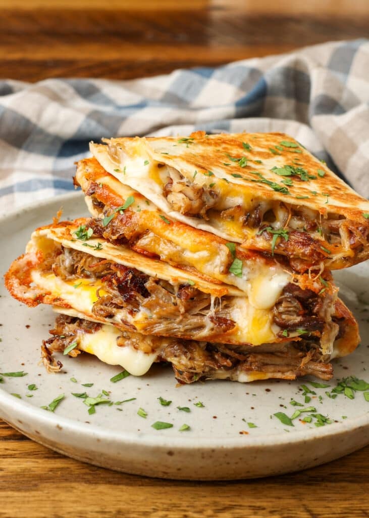 A black and white tea towel is visible in the background, behind a tall stack of quesadilla wedges.