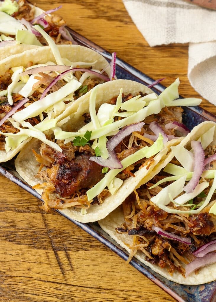 close up of pork tacos with cabbage, onion, and cilantro topppings