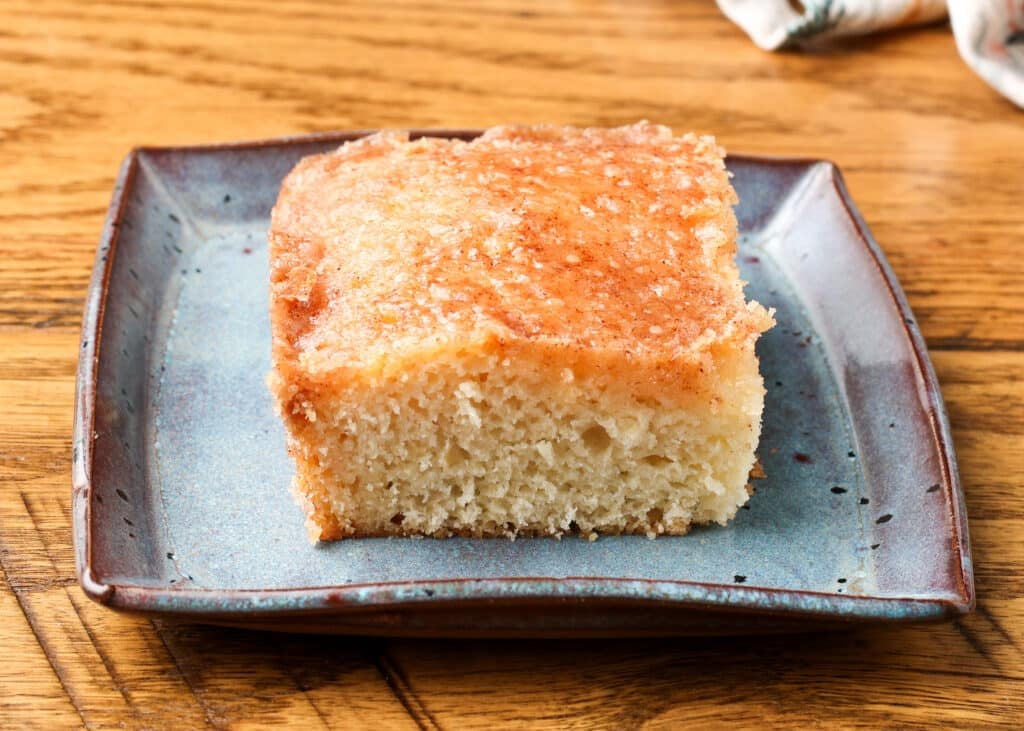A single serving of cinnamon toast cake on a blue and brown ceramic square plate.