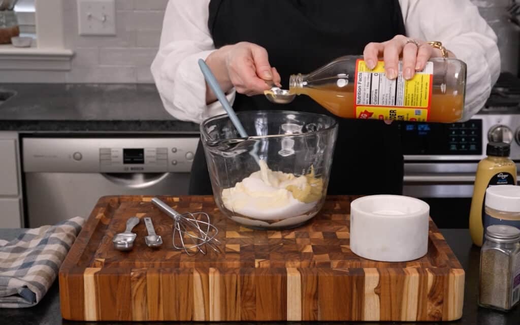 A horizontally aligned image Mary measuring the ingredients into a mixing bowl.