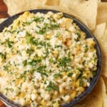 close up overhead photo of Elote Corn Dip with tortilla chips around the bowl