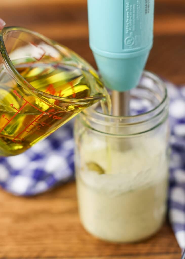 slowly pouring oil into dressing while blending