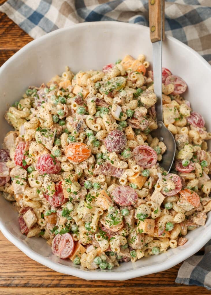 A top down shot of the white bowl loaded with Chicken Bacon Ranch Pasta Salad on a wooden tabletop.