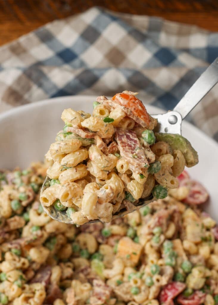 A close up on a metal spoon full of Chicken Bacon Ranch Pasta Salad in the foreground.
