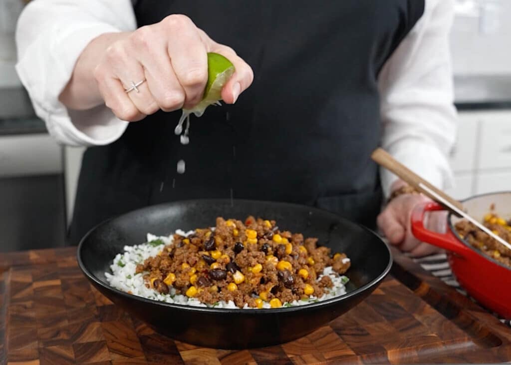 squeezing lime juice over a taco bowl