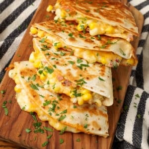 stacked quesadillas filled with corn on cutting board