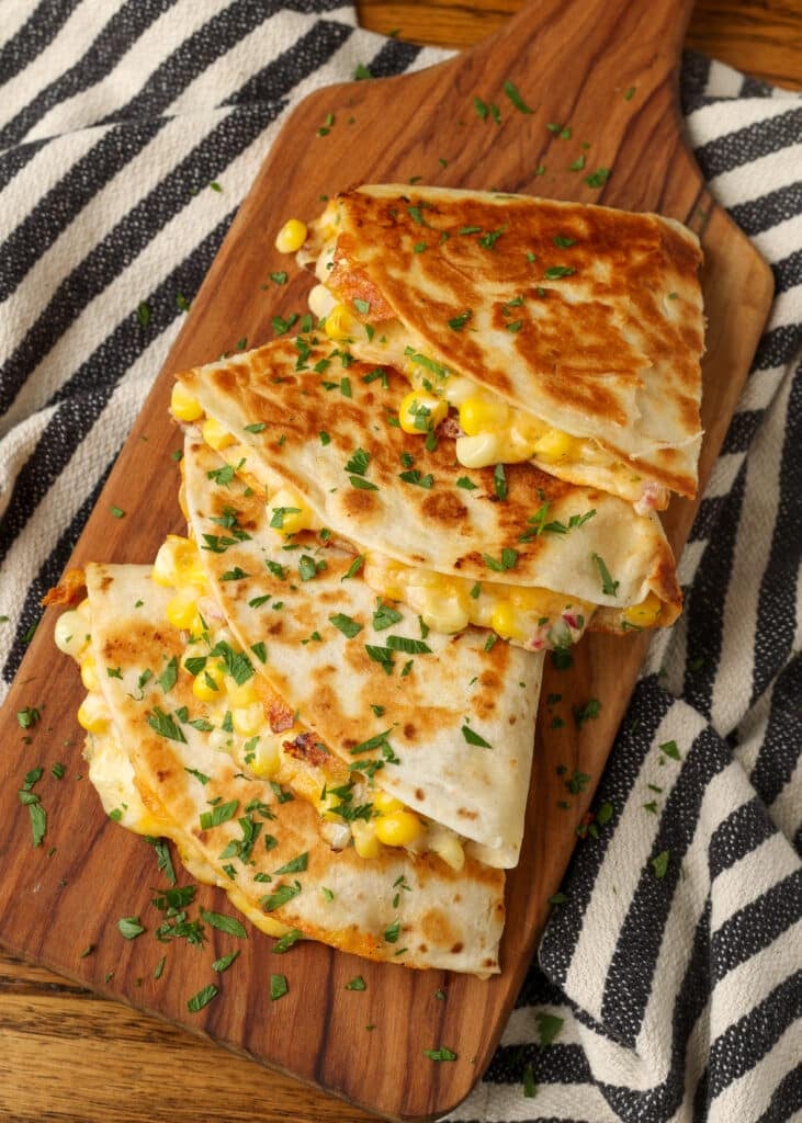 Corn quesadillas stacked vertically on board