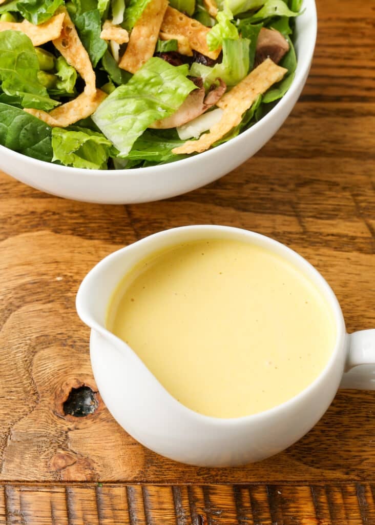 closeup of honey mustard dressing in pitcher on wooden table