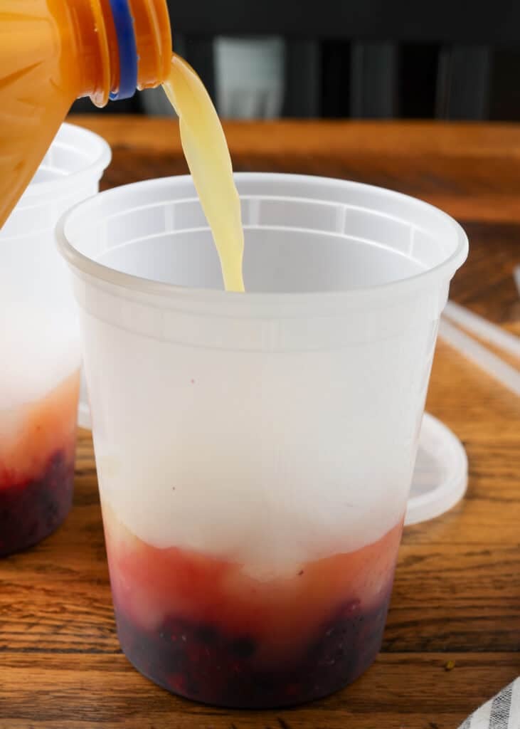pouring pineapple juice into a berry mocktail