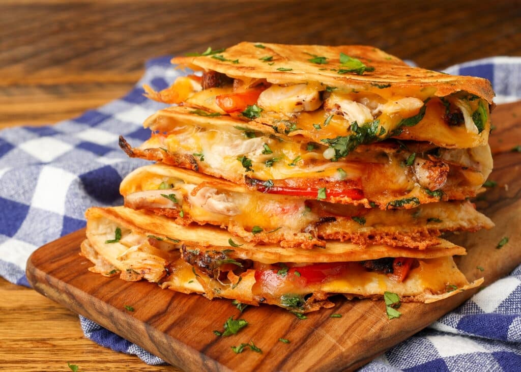 stacked quesadillas on board next to blue and white napkin