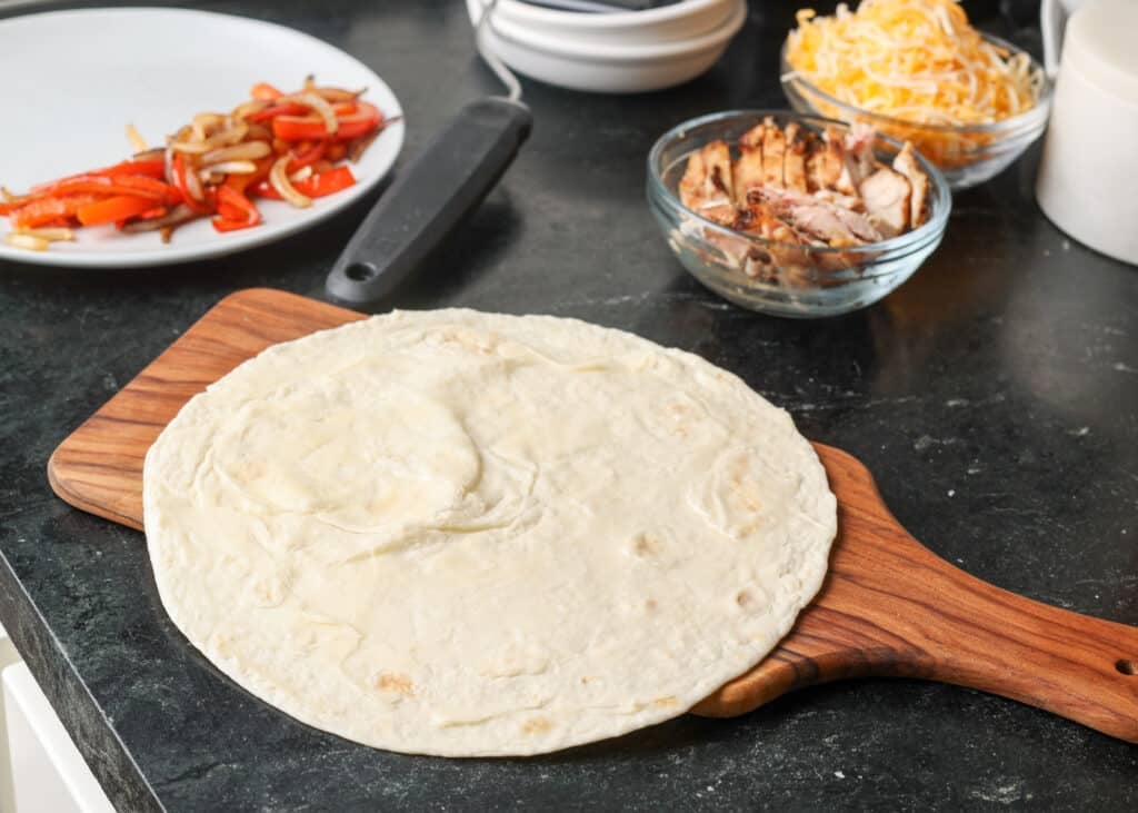 buttering tortilla next to stove