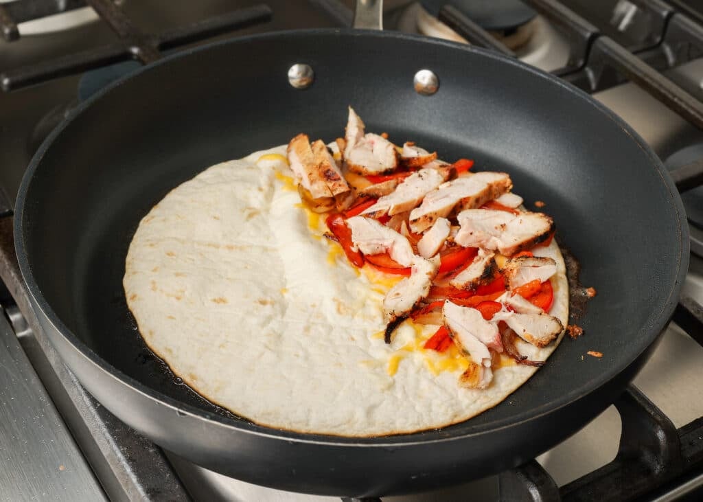 adding chicken to tortilla for quesadilla