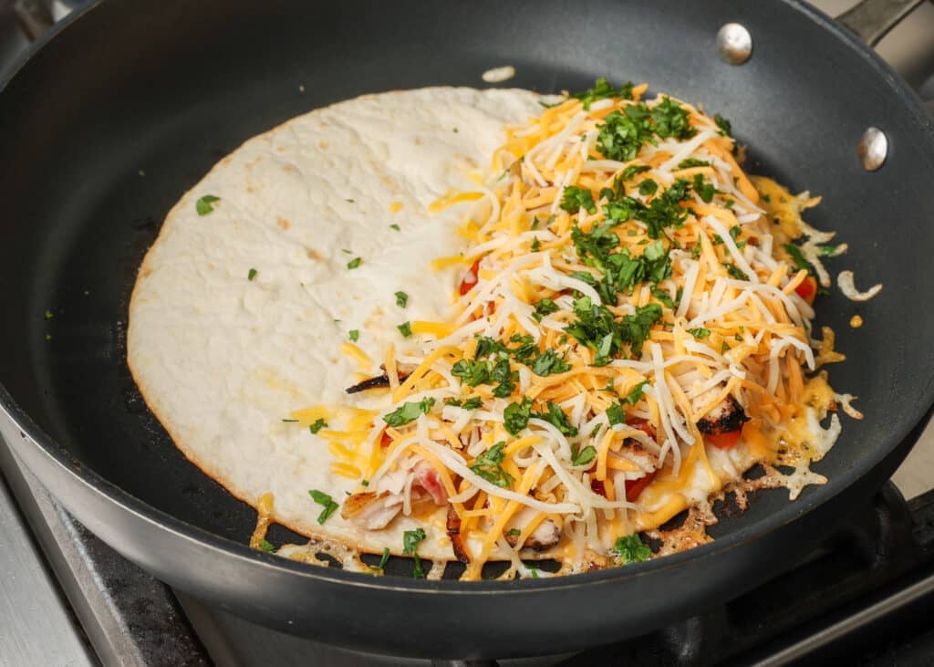adding final layer of cheese to tortilla for quesadilla