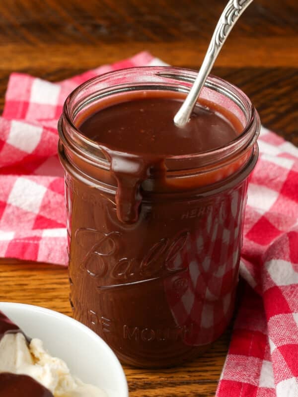jar of fudge sauce with drip on side and silver ladle