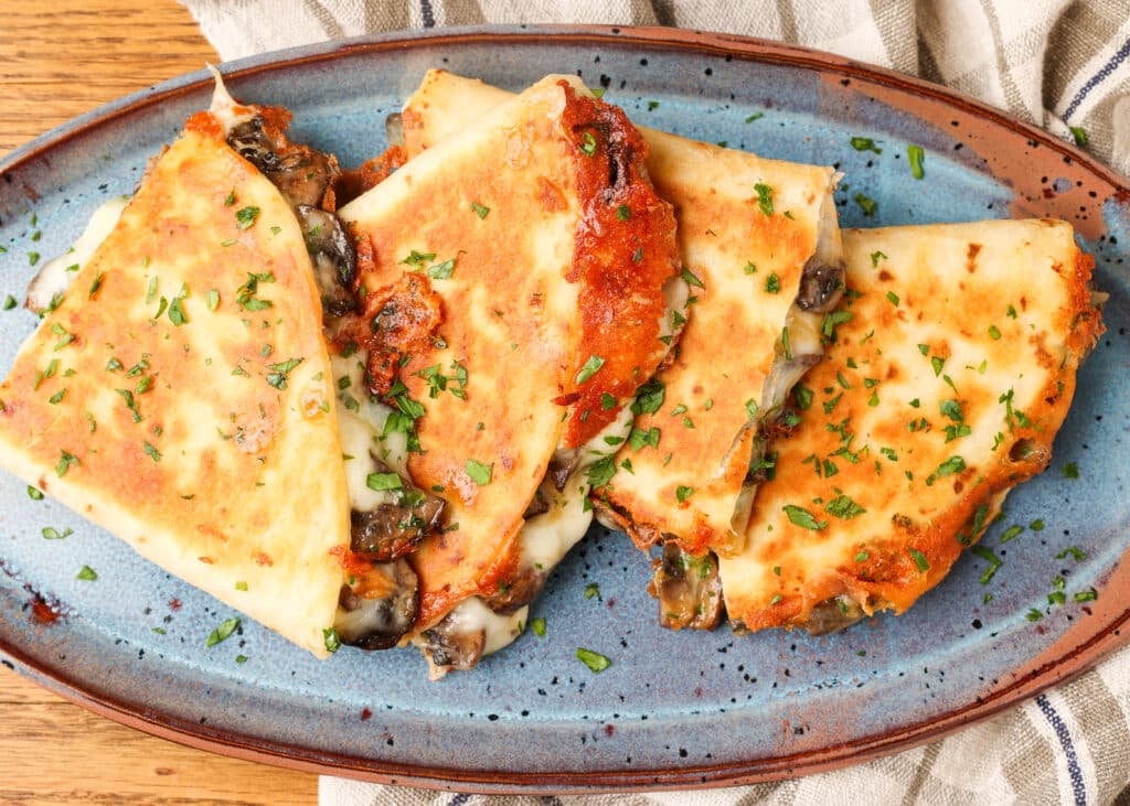 layered quesadillas with garlicky mushrooms on blue pottery plate