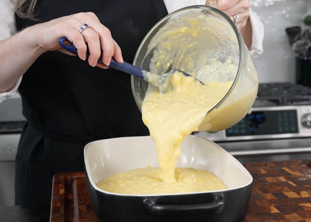 pouring corn pudding batter into baking dish